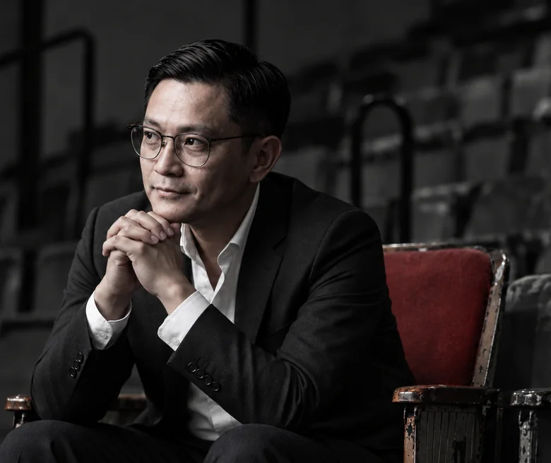 Ziqian seated in a quiet cinema, one red seat beside him
